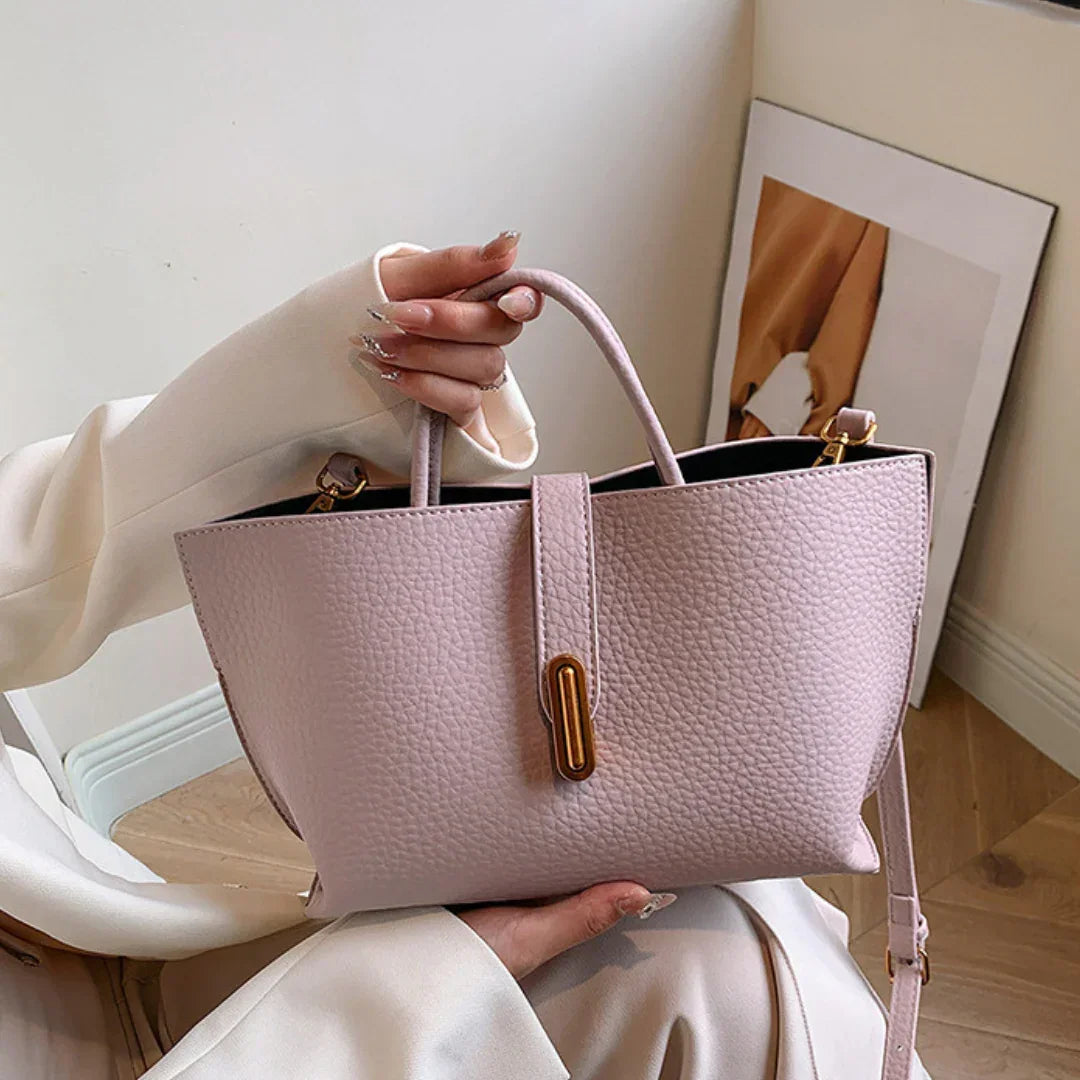 Woman holding a textured pink leather handbag with gold hardware indoors