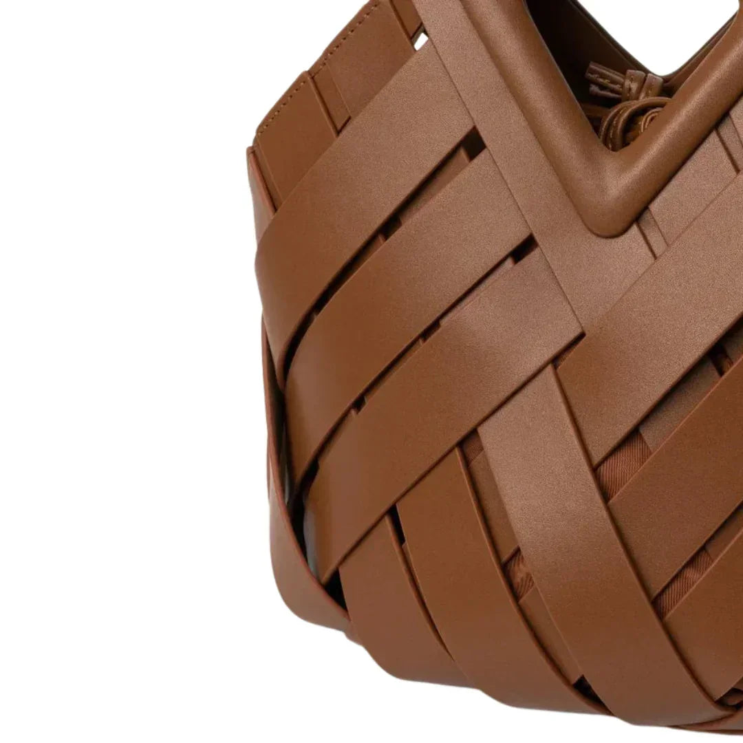 Close-up of brown woven leather handbag with geometric design against white background