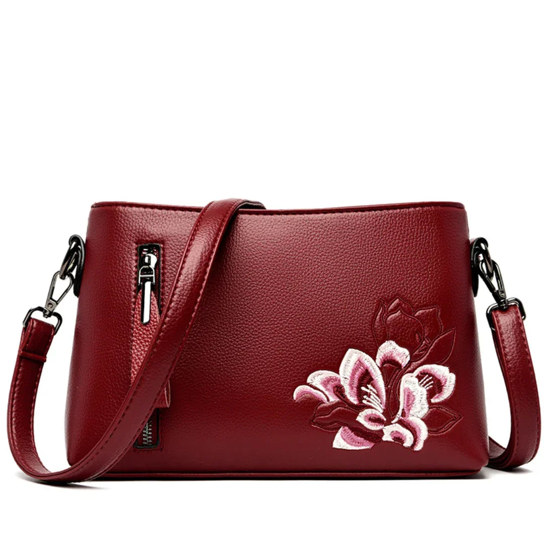 Red leather crossbody bag with pink floral embroidery and front zipper pocket