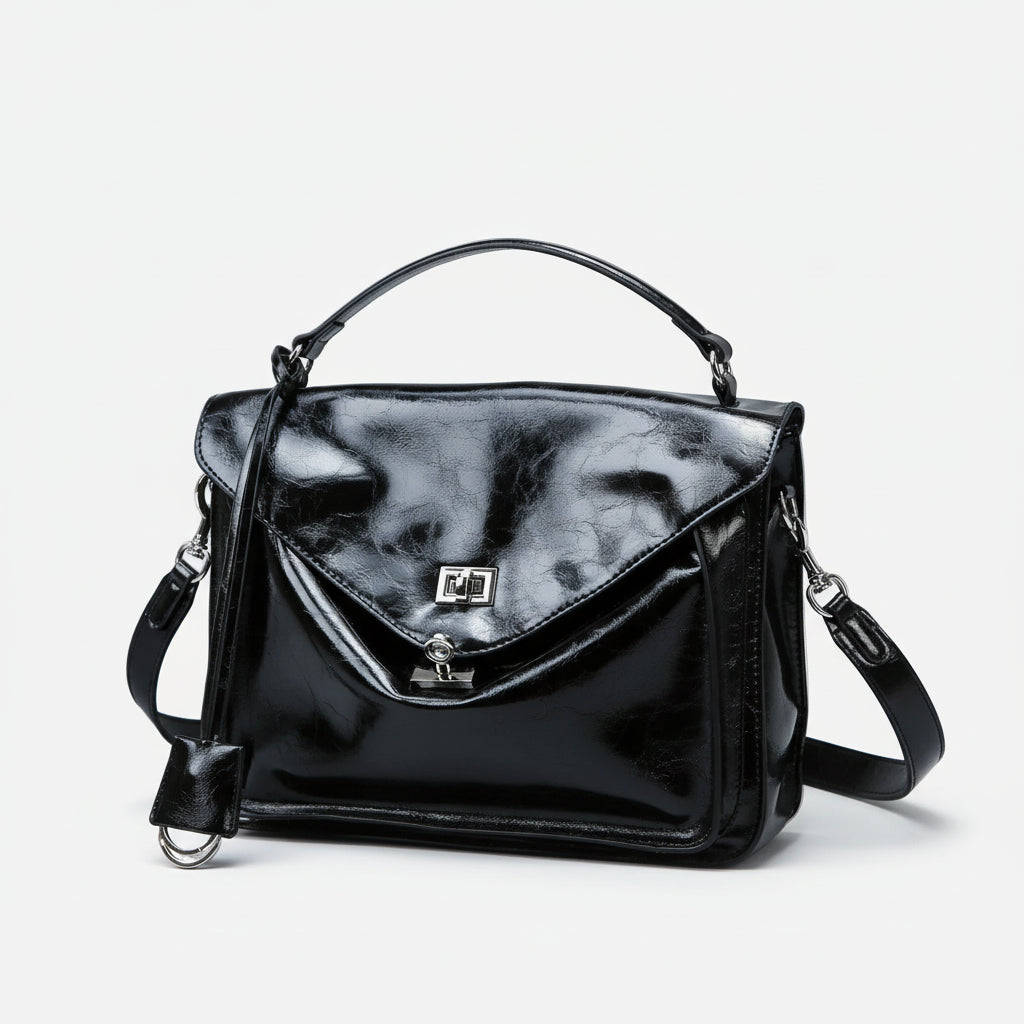 Glossy black leather handbag with top handle, flap closure, and shoulder strap on white background