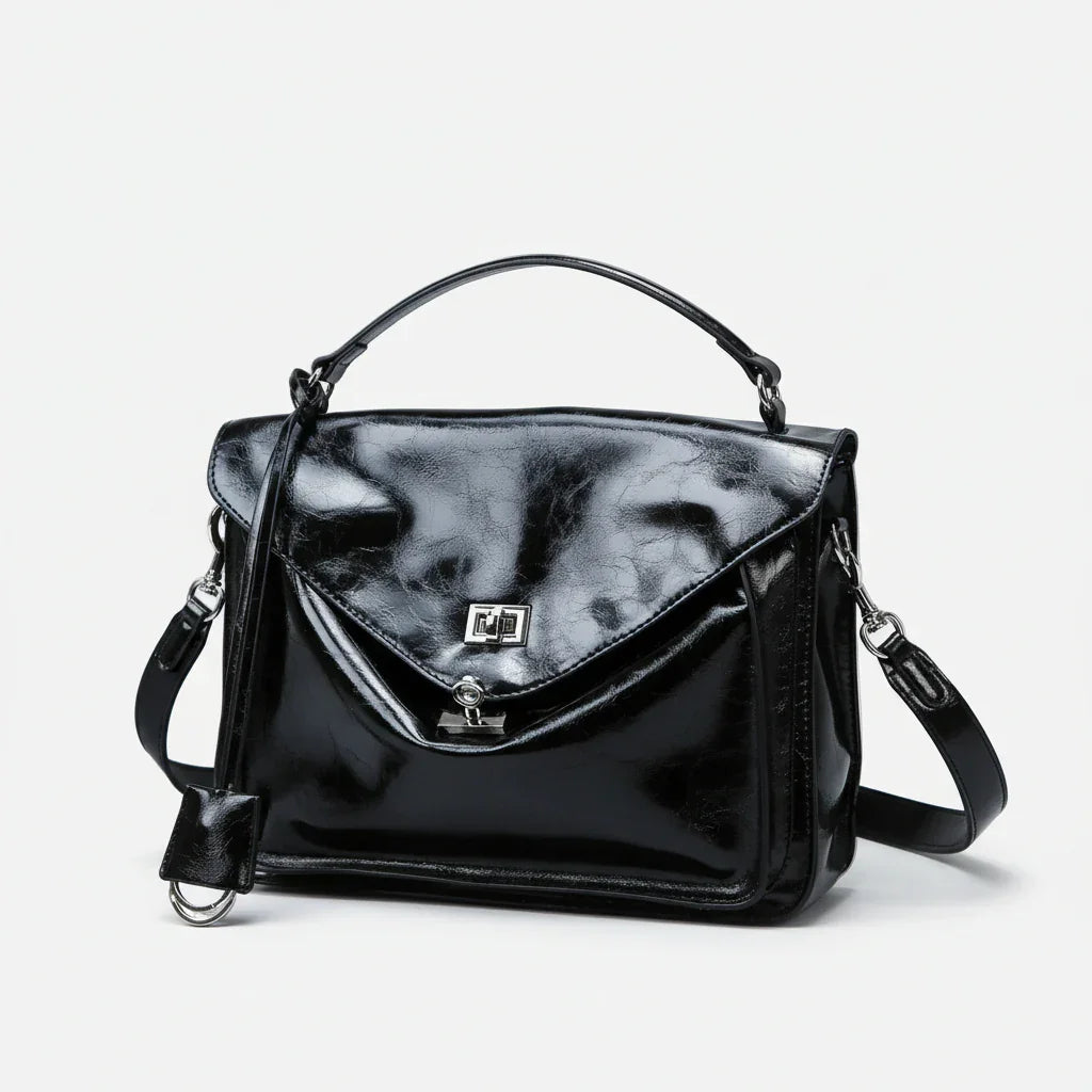 Glossy black leather handbag with top handle, flap closure, and shoulder strap on white background