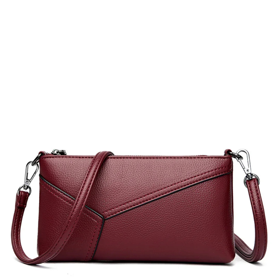 Burgundy leather crossbody purse with geometric stitching and removable strap on white background