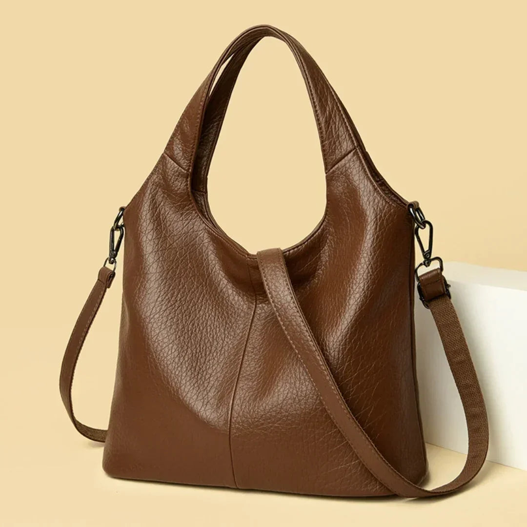 Brown leather shoulder bag with detachable strap on beige background