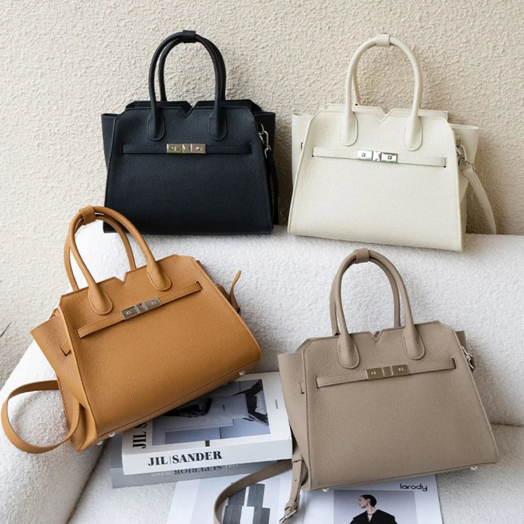 Four structured leather handbags in black, white, tan, and beige on a textured surface