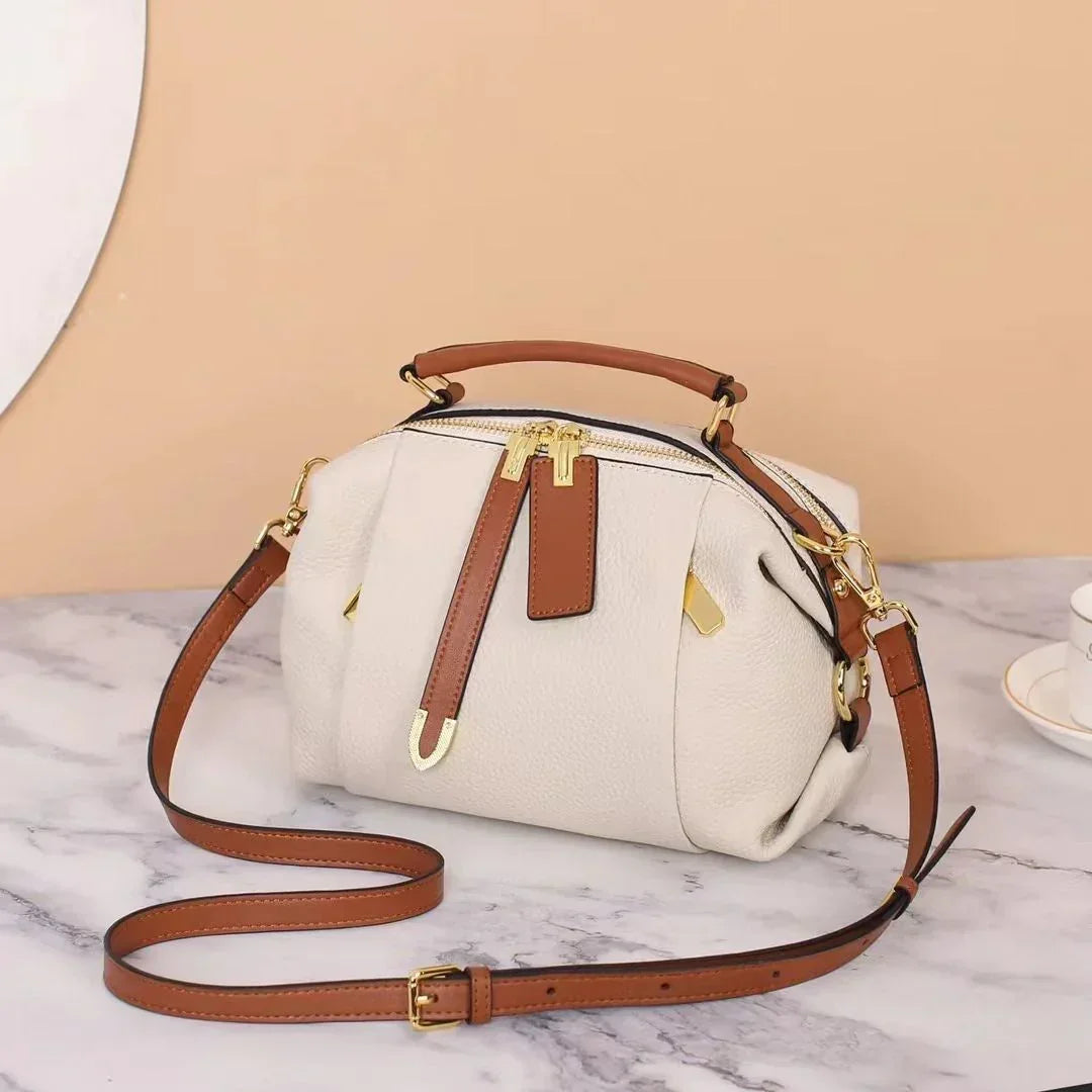 White leather handbag with brown straps and gold hardware on marble surface