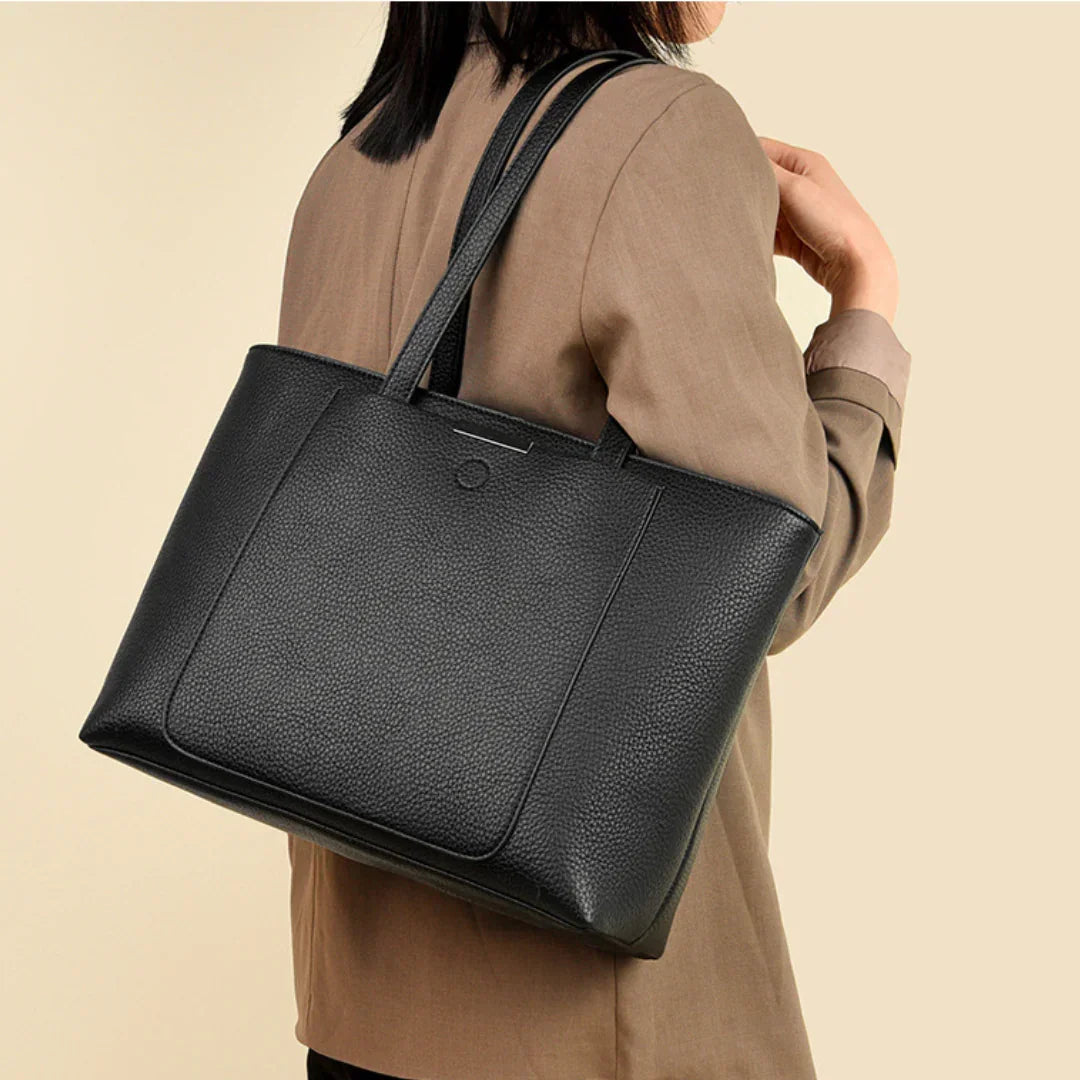 Woman in beige blazer carrying a large black leather tote bag