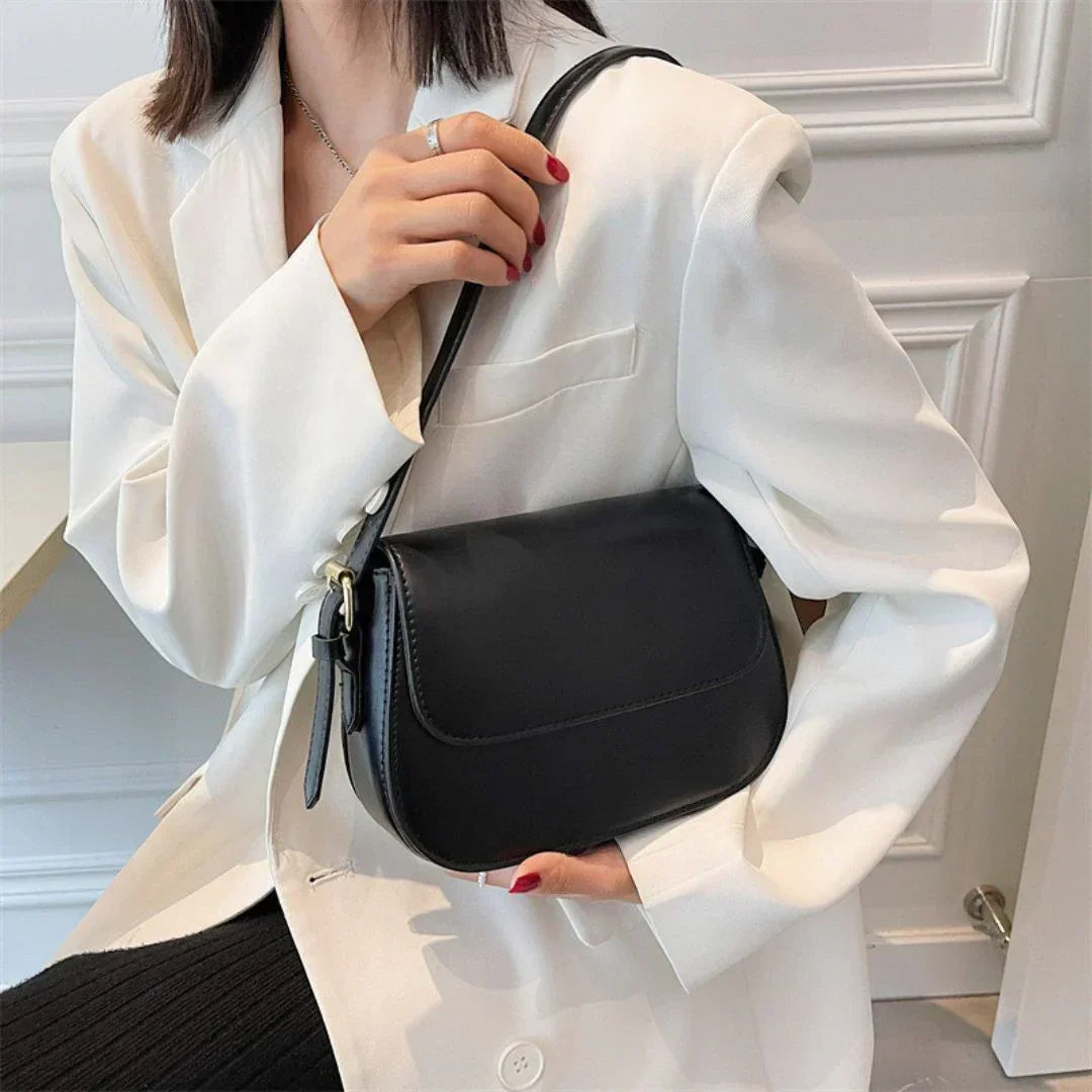 Woman in white blazer holding black leather shoulder bag