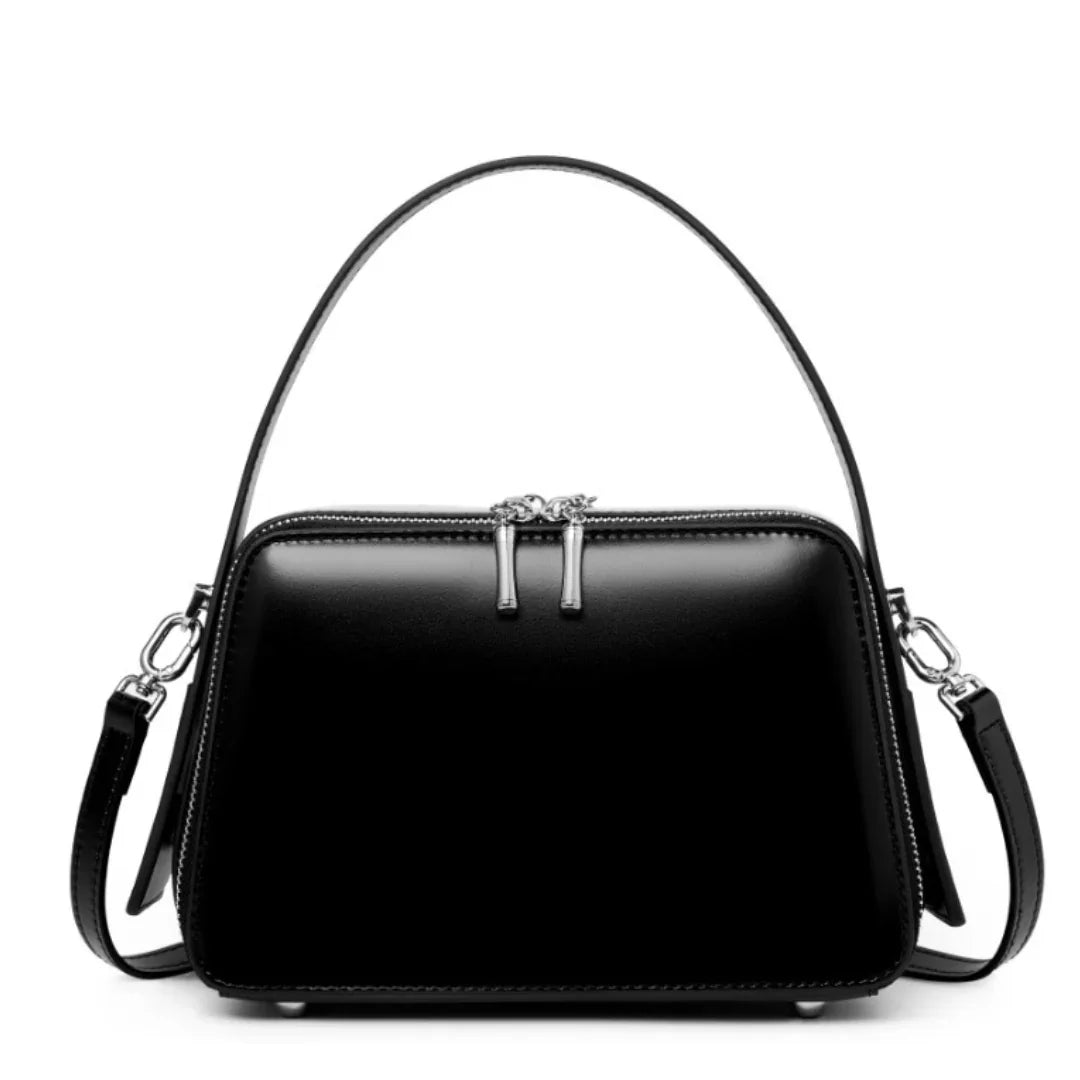 Black leather handbag with silver hardware and detachable shoulder strap on white background