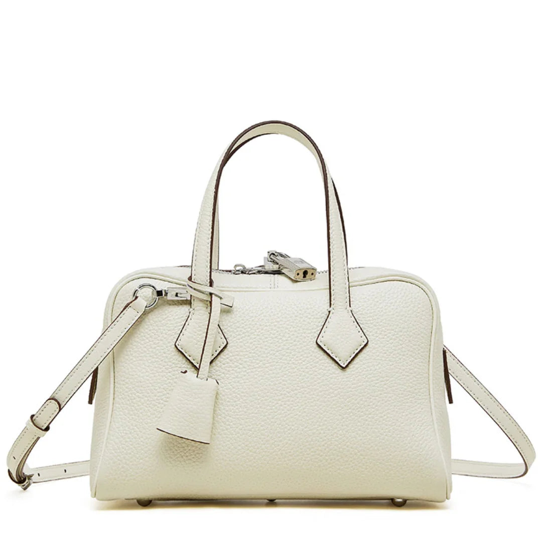 Cream leather handbag with top handles, shoulder strap, and silver hardware on white background