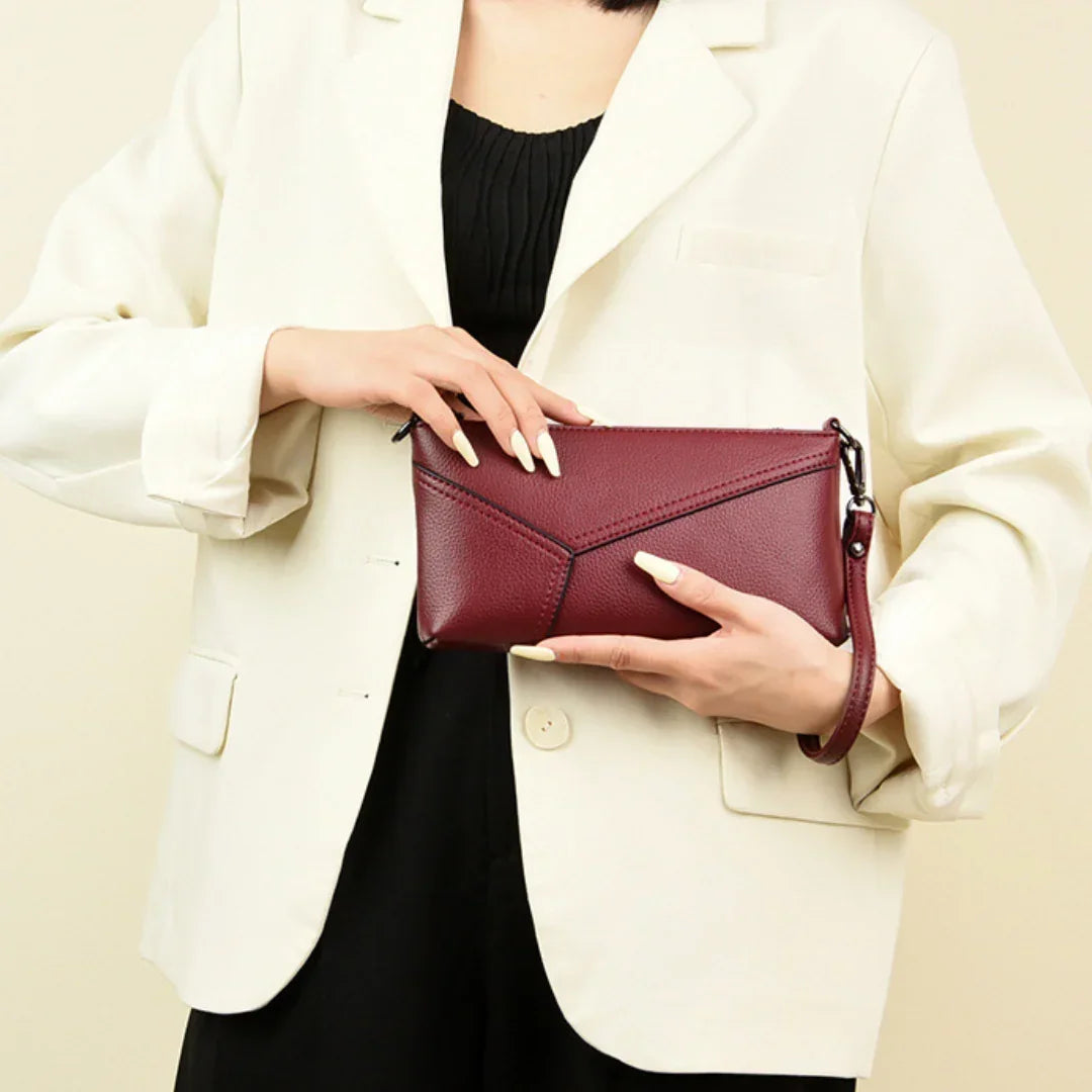 Woman in white blazer holding a burgundy leather wristlet clutch purse