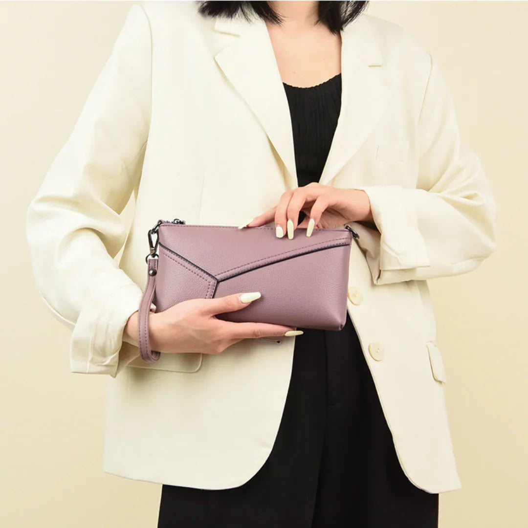 Woman in cream blazer holding a purple leather wristlet clutch bag