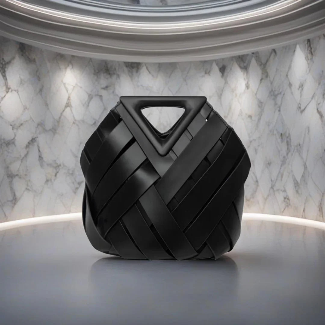 Modern black woven handbag with triangular handle on marble background