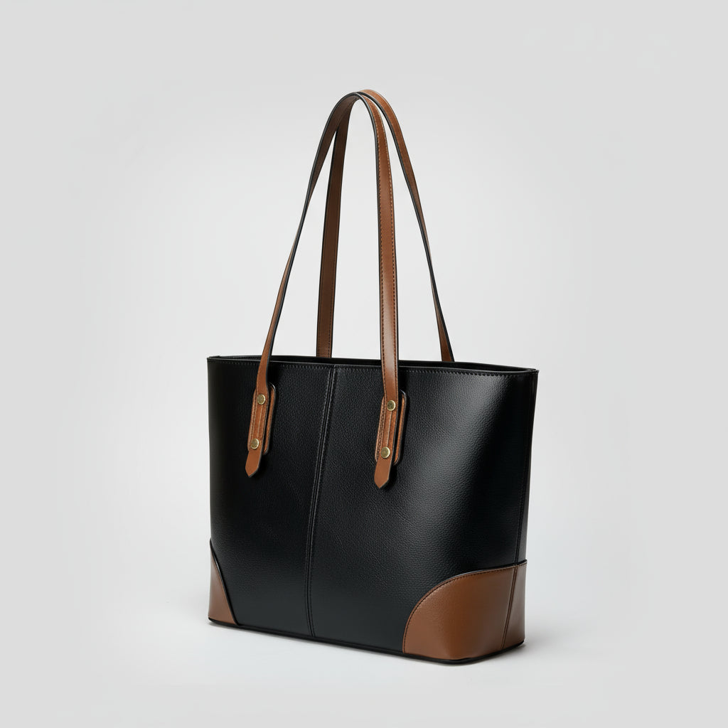 Black leather tote bag with brown handles and accents on a plain gray background