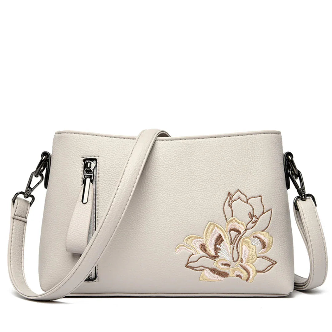 Beige leather crossbody bag with floral embroidery and front zipper pocket