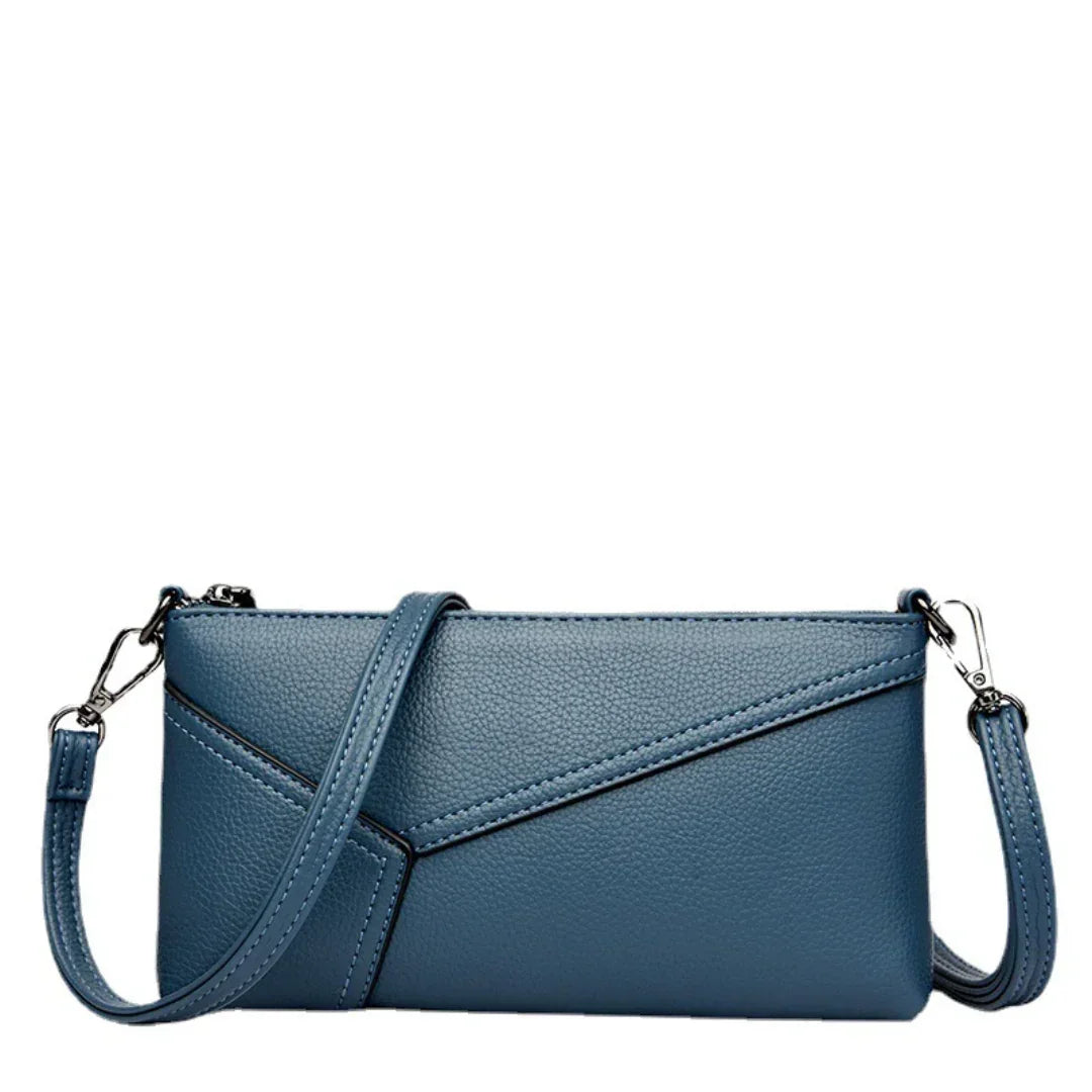 Blue faux leather crossbody bag with embossed texture and detachable strap on white background