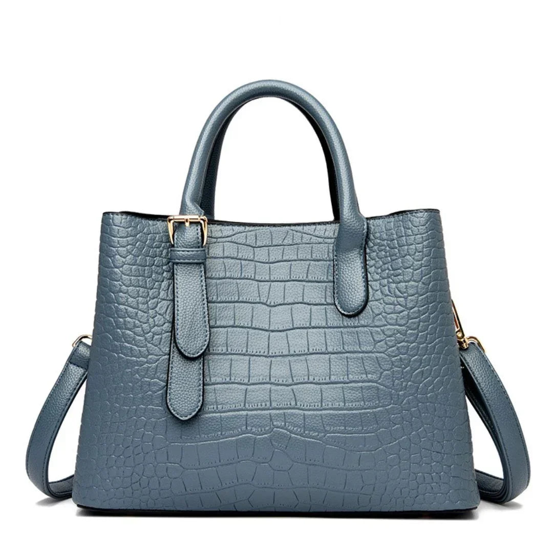 Blue crocodile pattern leather tote bag with top handles and shoulder strap on white background