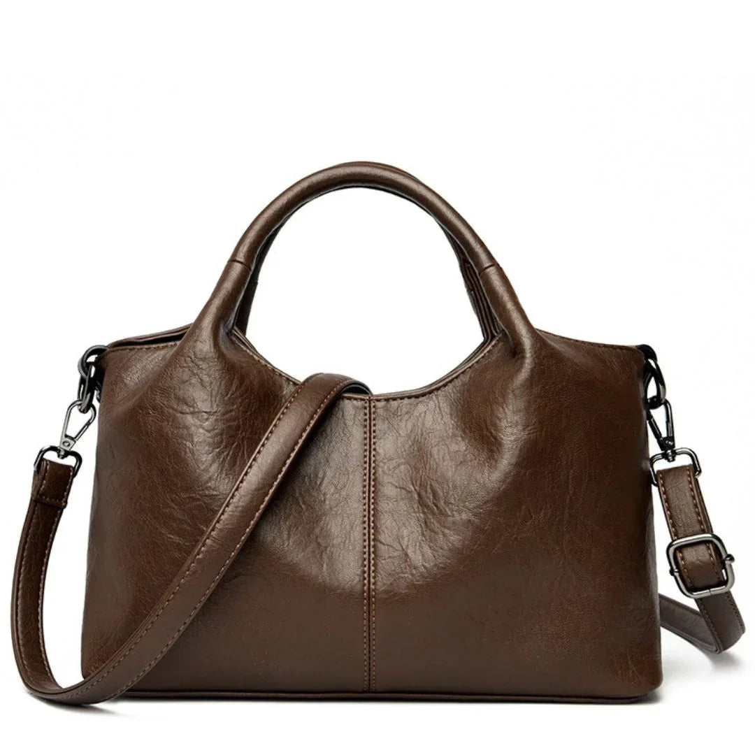 Brown leather handbag with shoulder strap and top handles on white background