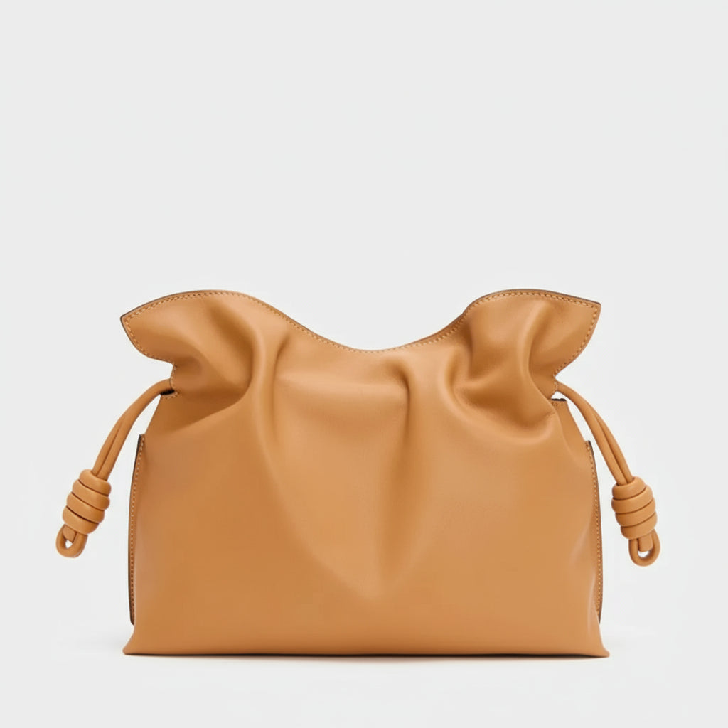 Tan leather clutch bag with ruffled top and knotted side drawstrings on white background