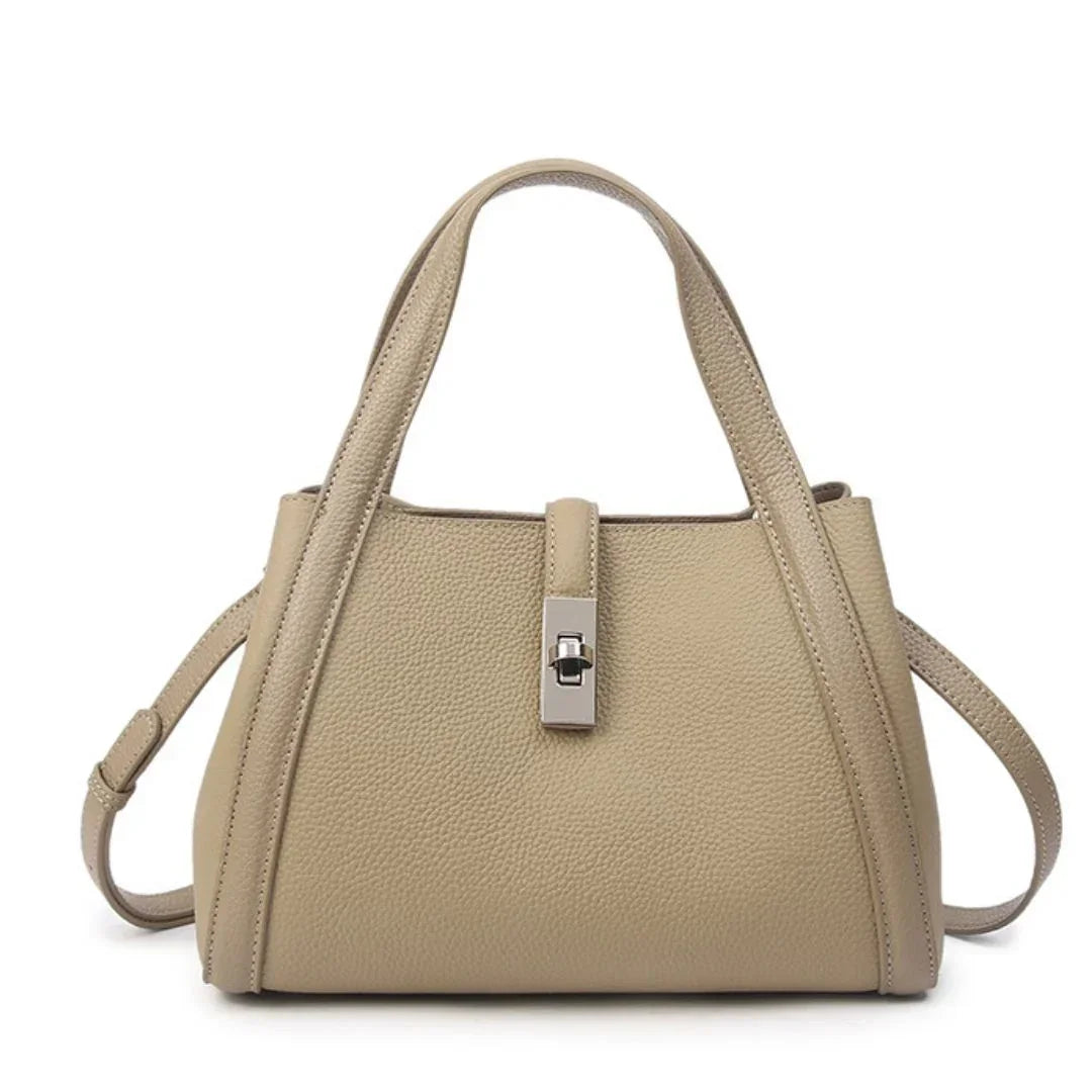 Beige leather handbag with top handles, pebbled texture, and silver turn-lock clasp