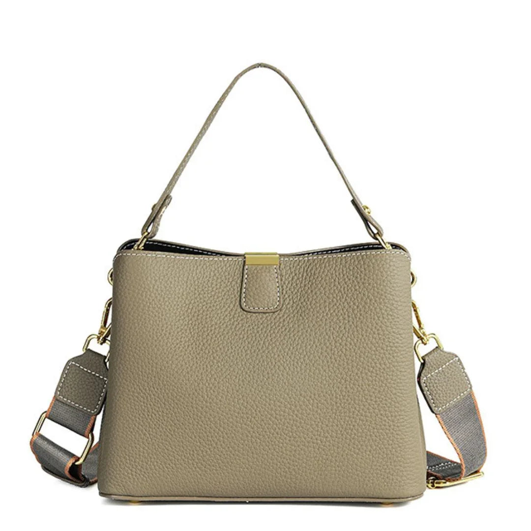 Taupe leather handbag with gold hardware and detachable shoulder strap on white background