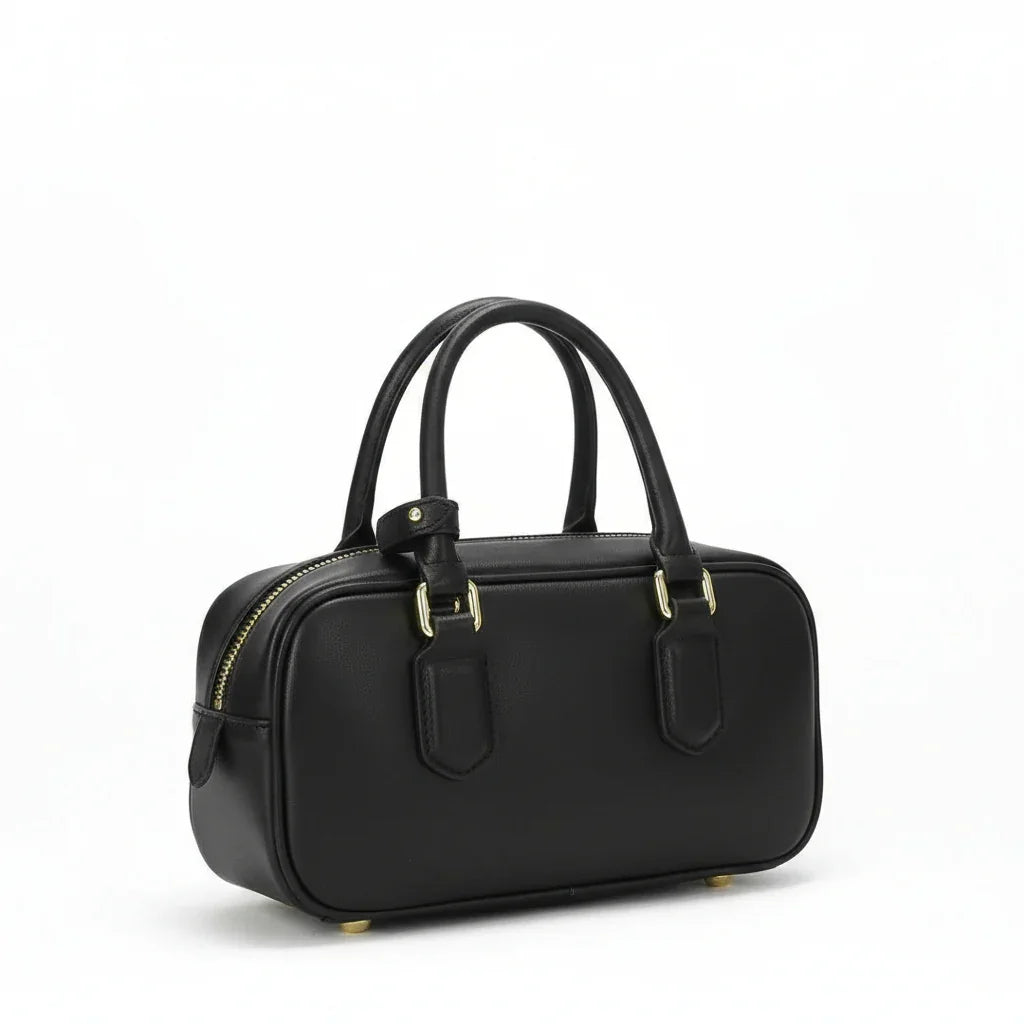 Black leather handbag with gold hardware and double handles on white background
