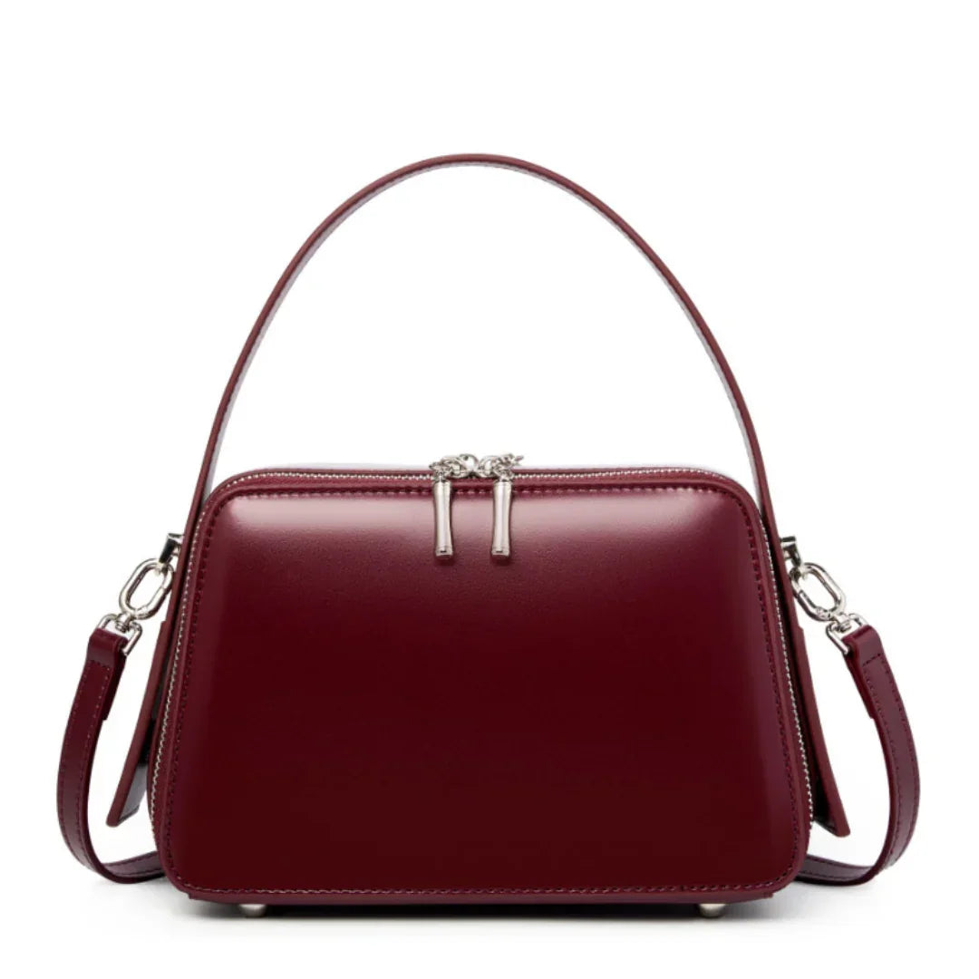 Elegant burgundy leather handbag with top handle, silver zipper, and detachable strap