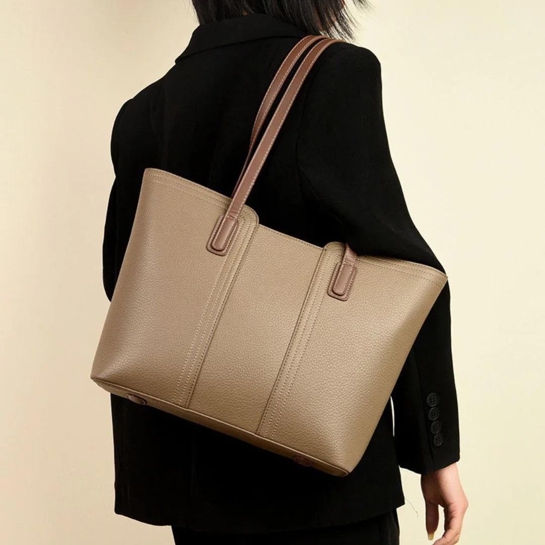 Woman in black blazer carrying a taupe leather tote bag with brown straps