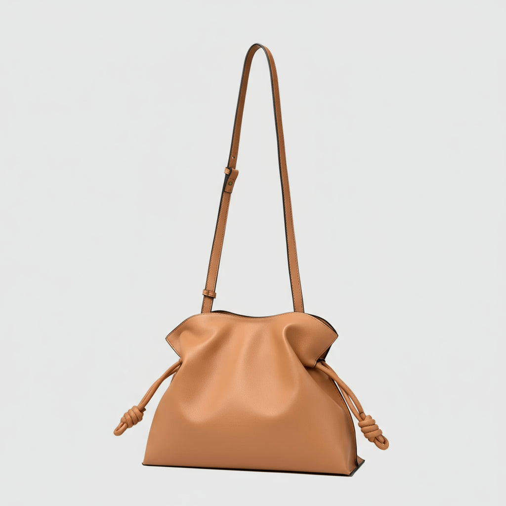 Tan leather knot bag with adjustable shoulder strap, minimalist purse on white background