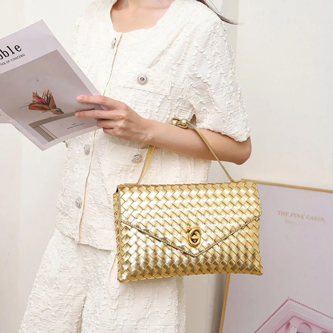 Woman in white textured outfit holding magazine and gold woven shoulder bag