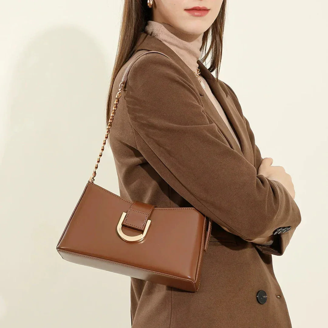 Woman in brown blazer with brown leather shoulder bag and gold hardware