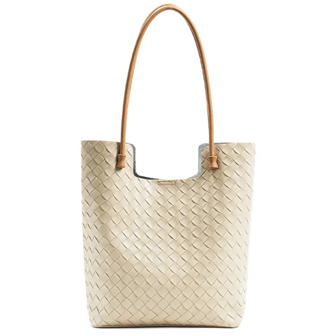 Beige woven leather tote bag with long brown handles on white background