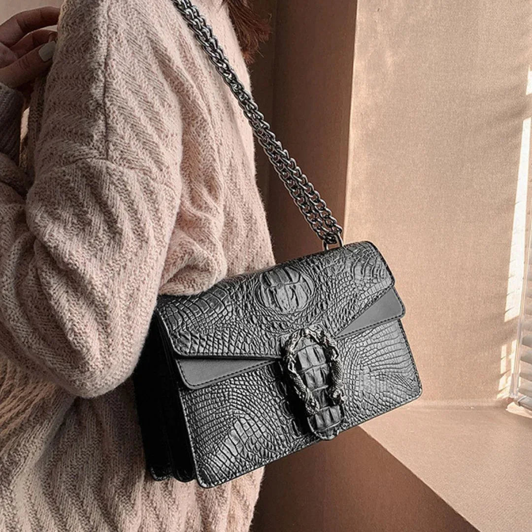 Woman wearing textured sweater with black crocodile pattern shoulder bag and chain strap