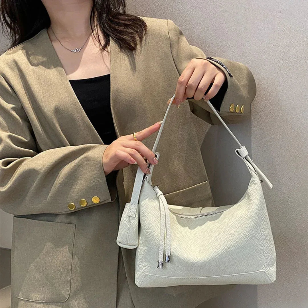 Woman in beige blazer holding a stylish white leather shoulder bag