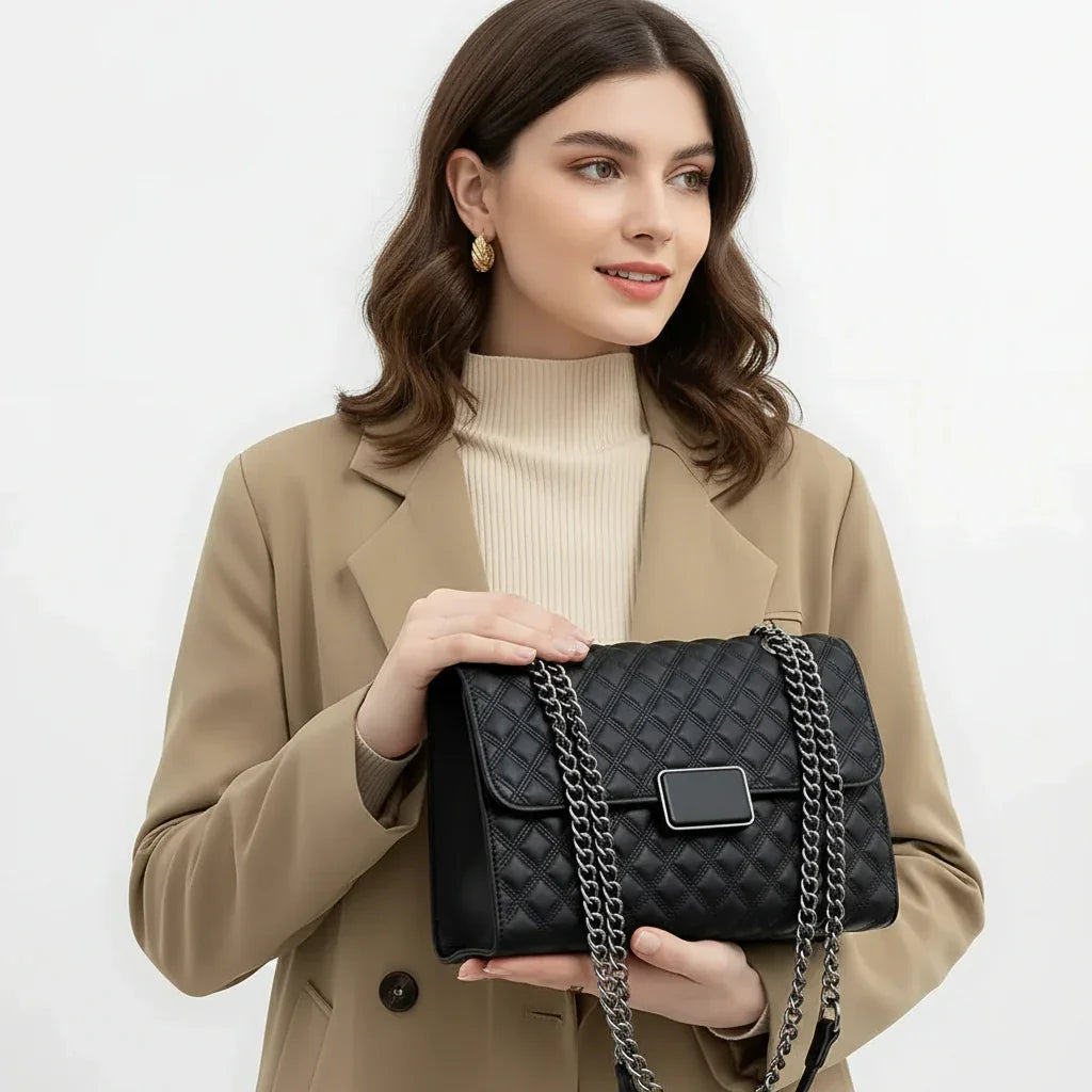 Woman in beige blazer holding black quilted chain shoulder bag, fashion accessories