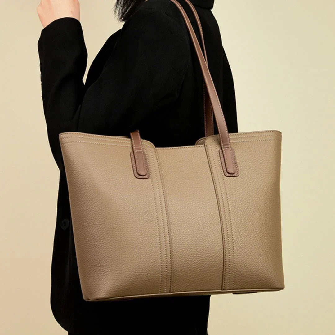 Woman in black blazer carrying a beige leather tote bag with brown handles