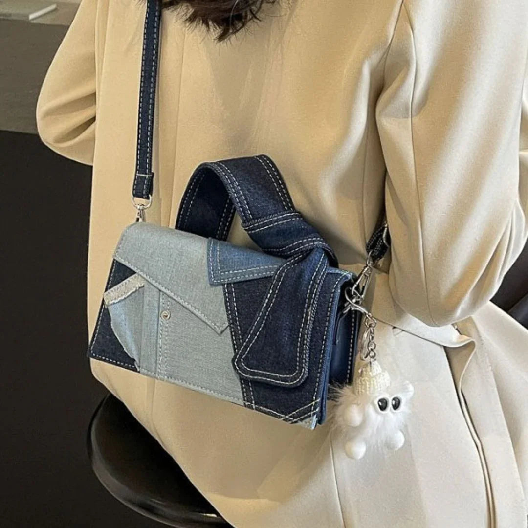 Woman wearing cream blazer with denim patchwork crossbody bag and fluffy keychain charm