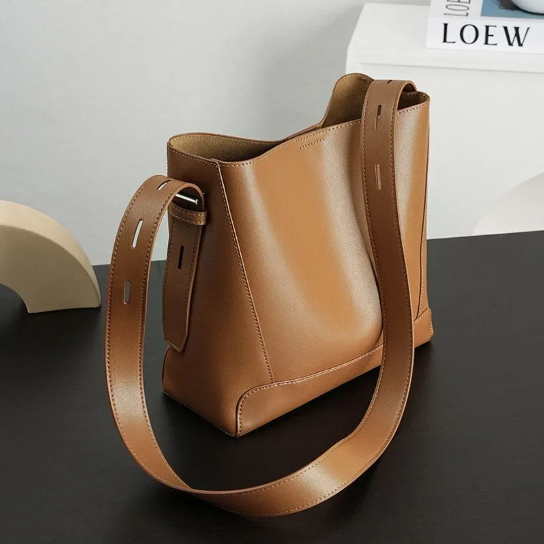 Minimalist brown leather shoulder bag on black desk, modern decor, fashion accessory