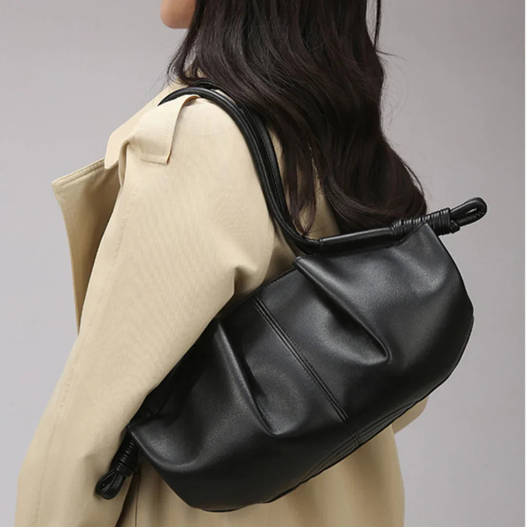 Woman wearing a beige coat and carrying a black leather shoulder bag
