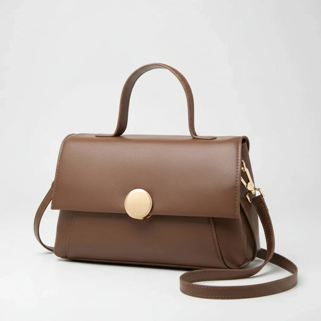 Brown leather handbag with top handle, gold clasp, and shoulder strap on white background