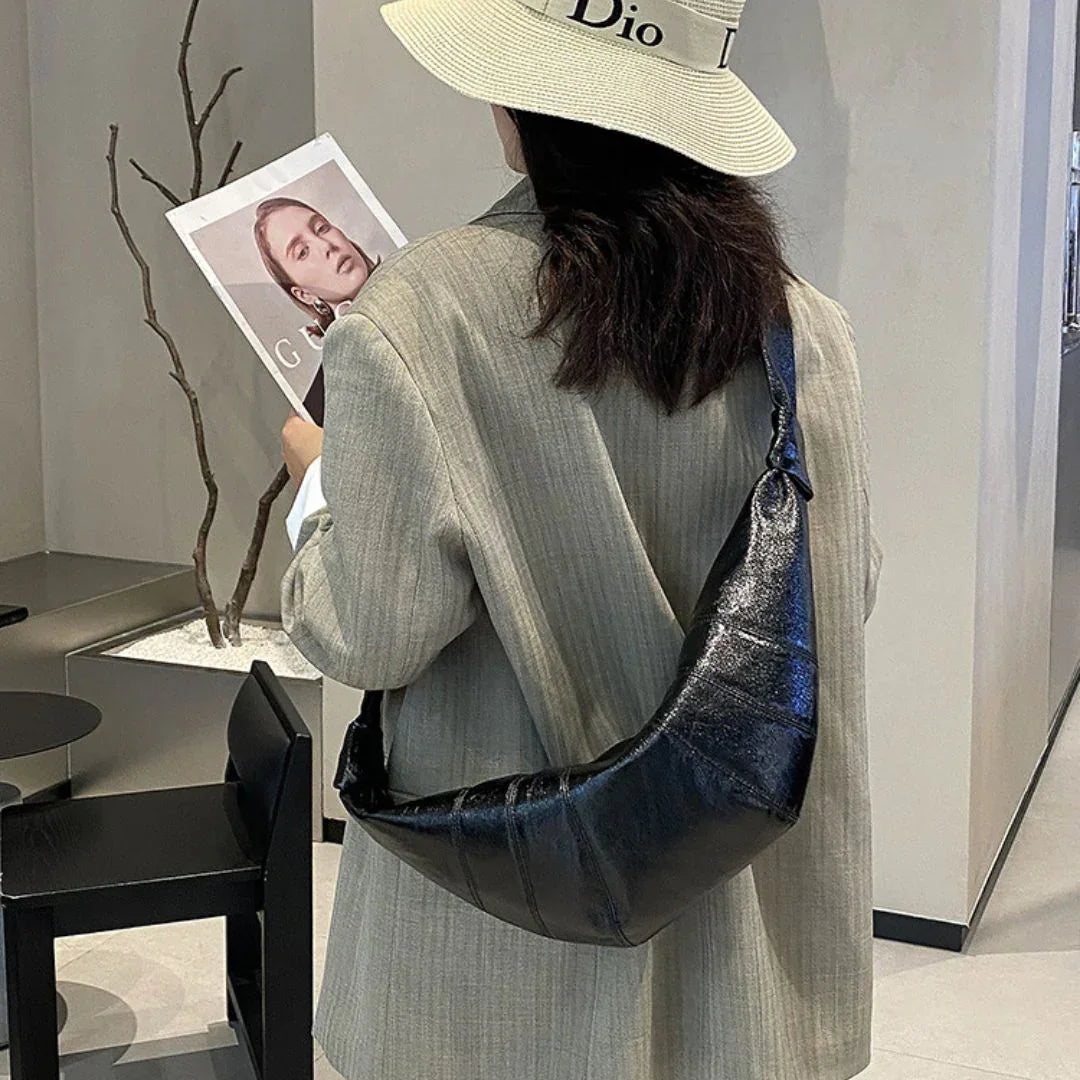 Woman in beige blazer and Dior hat with black crescent shoulder bag, holding magazine indoors