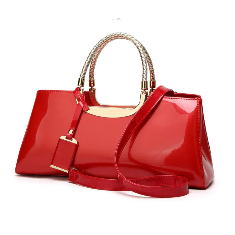 Glossy red patent leather handbag with gold accents and braided handles