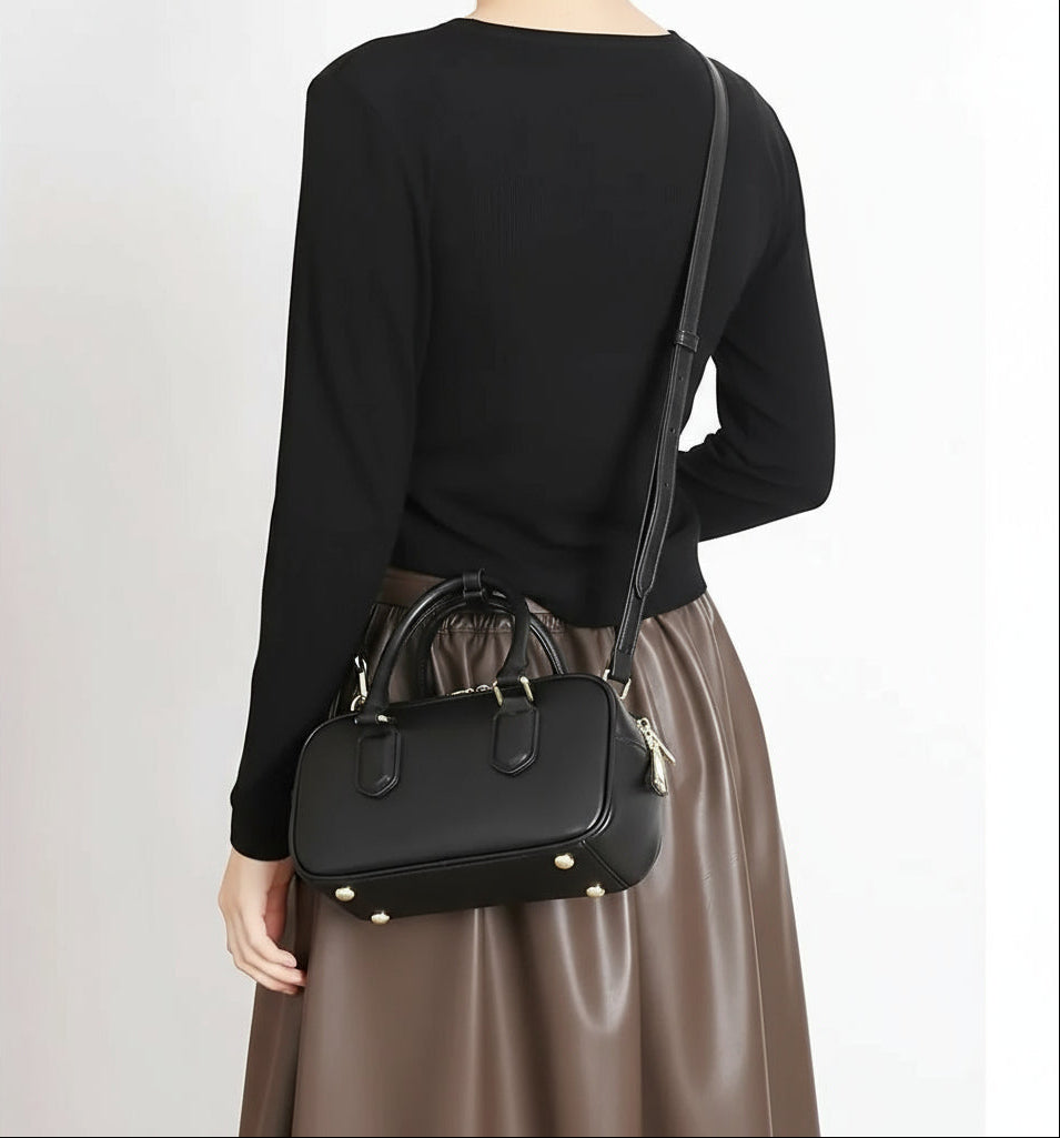 Woman wearing a black crossbody bag and brown skirt, stylish minimalist fashion