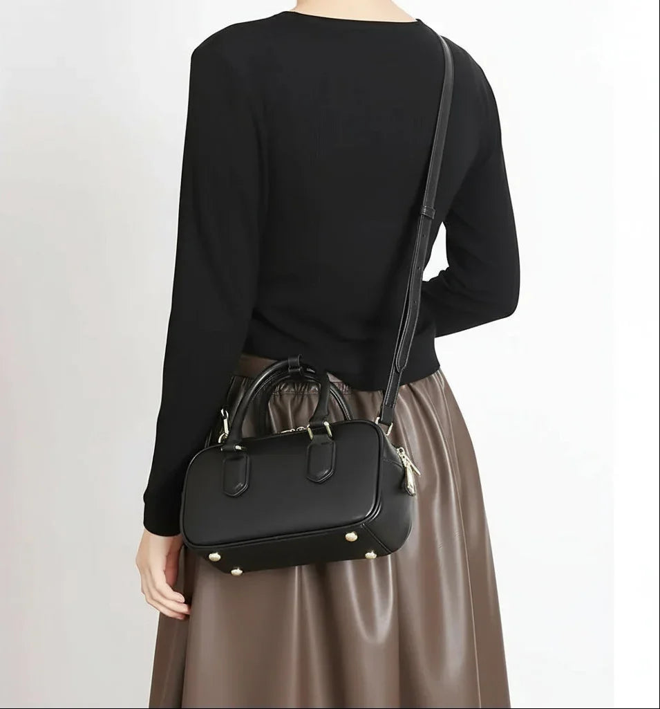 Woman wearing a black crossbody bag and brown skirt, stylish minimalist fashion