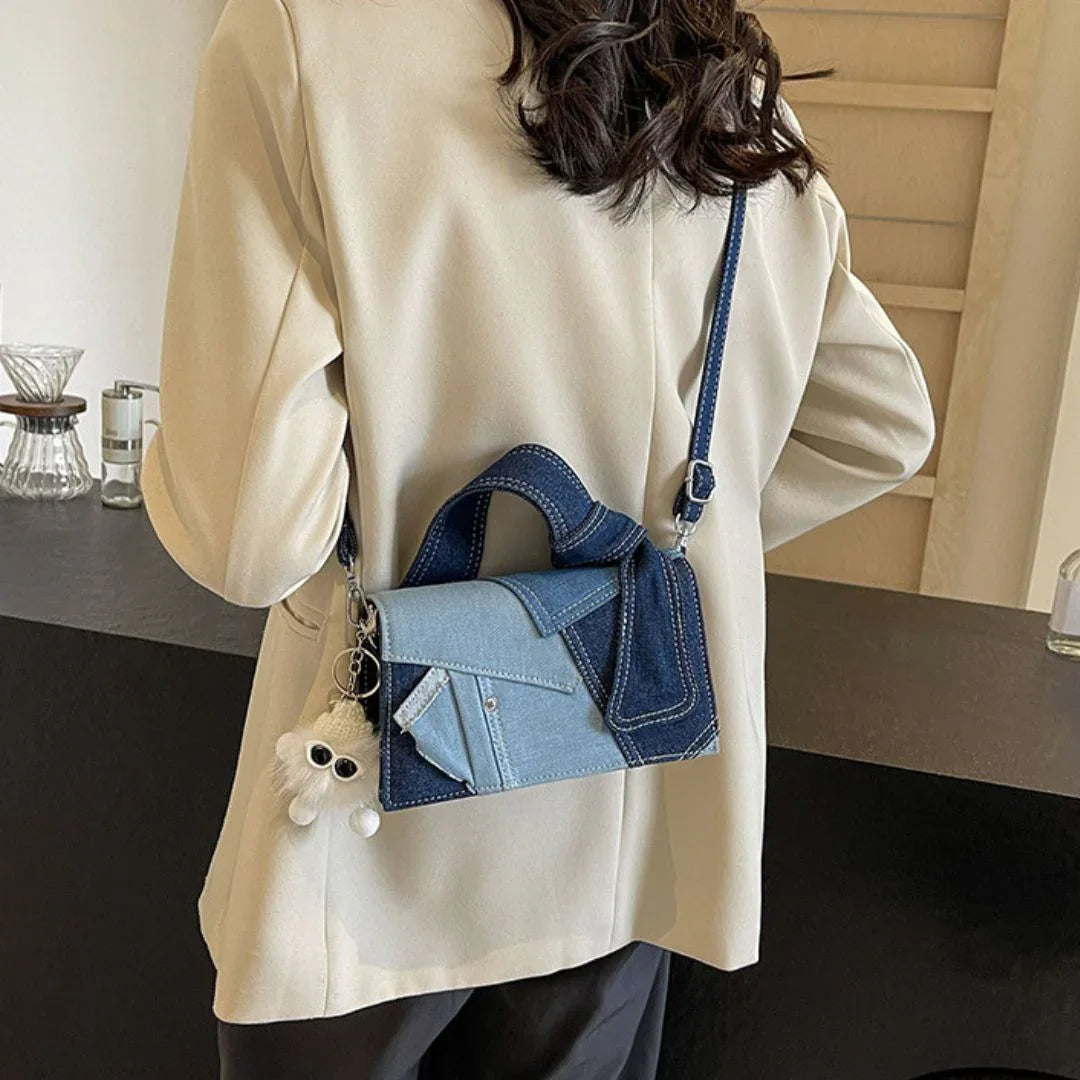Woman in beige blazer with denim crossbody bag and fluffy keychain