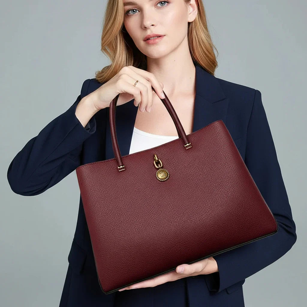 Woman in navy blazer holding large burgundy leather tote bag with gold hardware