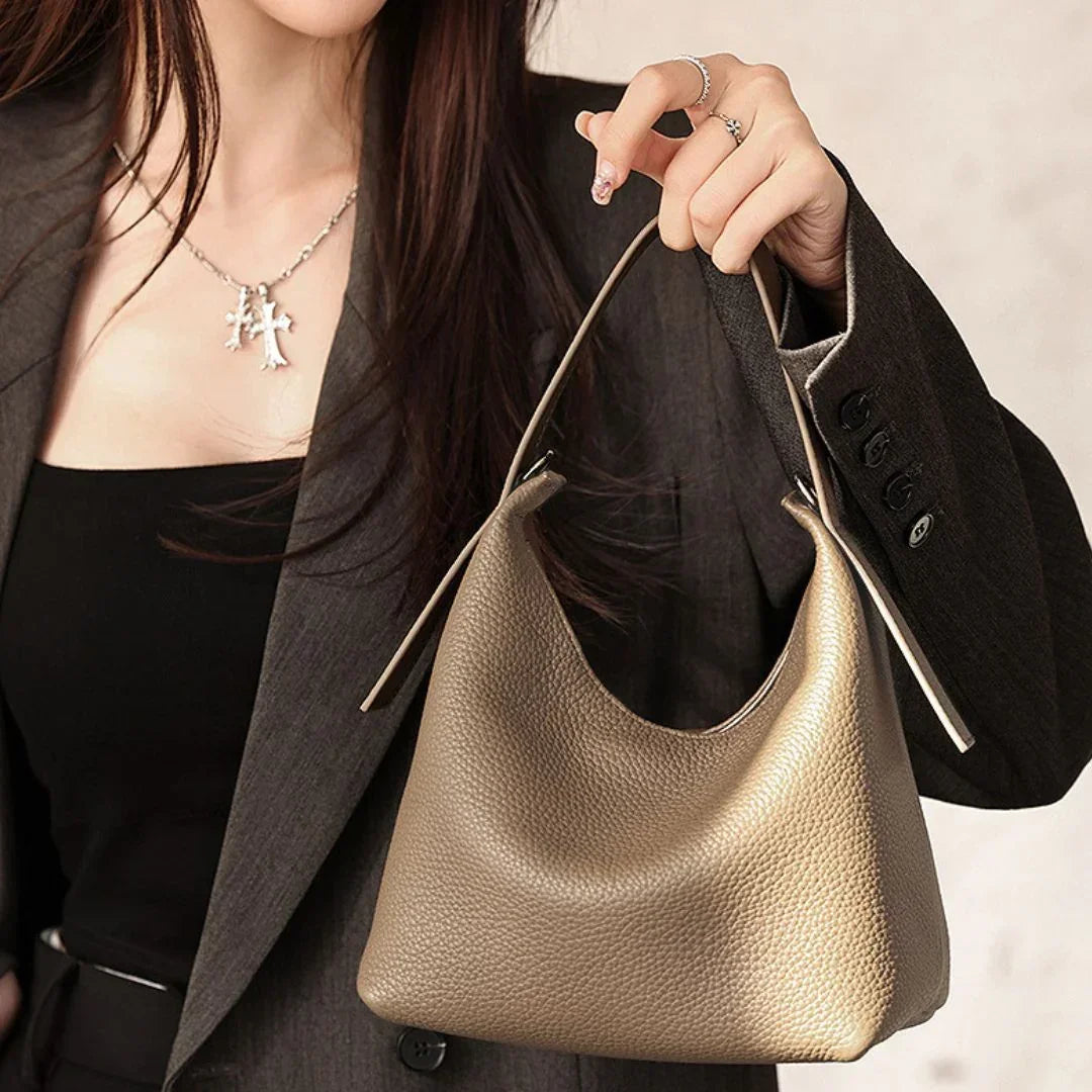 Woman in blazer holding metallic gold textured hobo bag, elegant fashion accessory