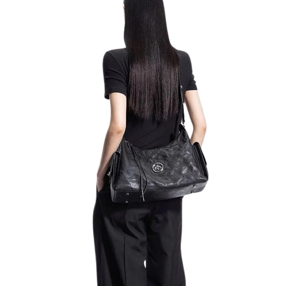 Woman in black outfit carrying large black leather shoulder bag on white background
