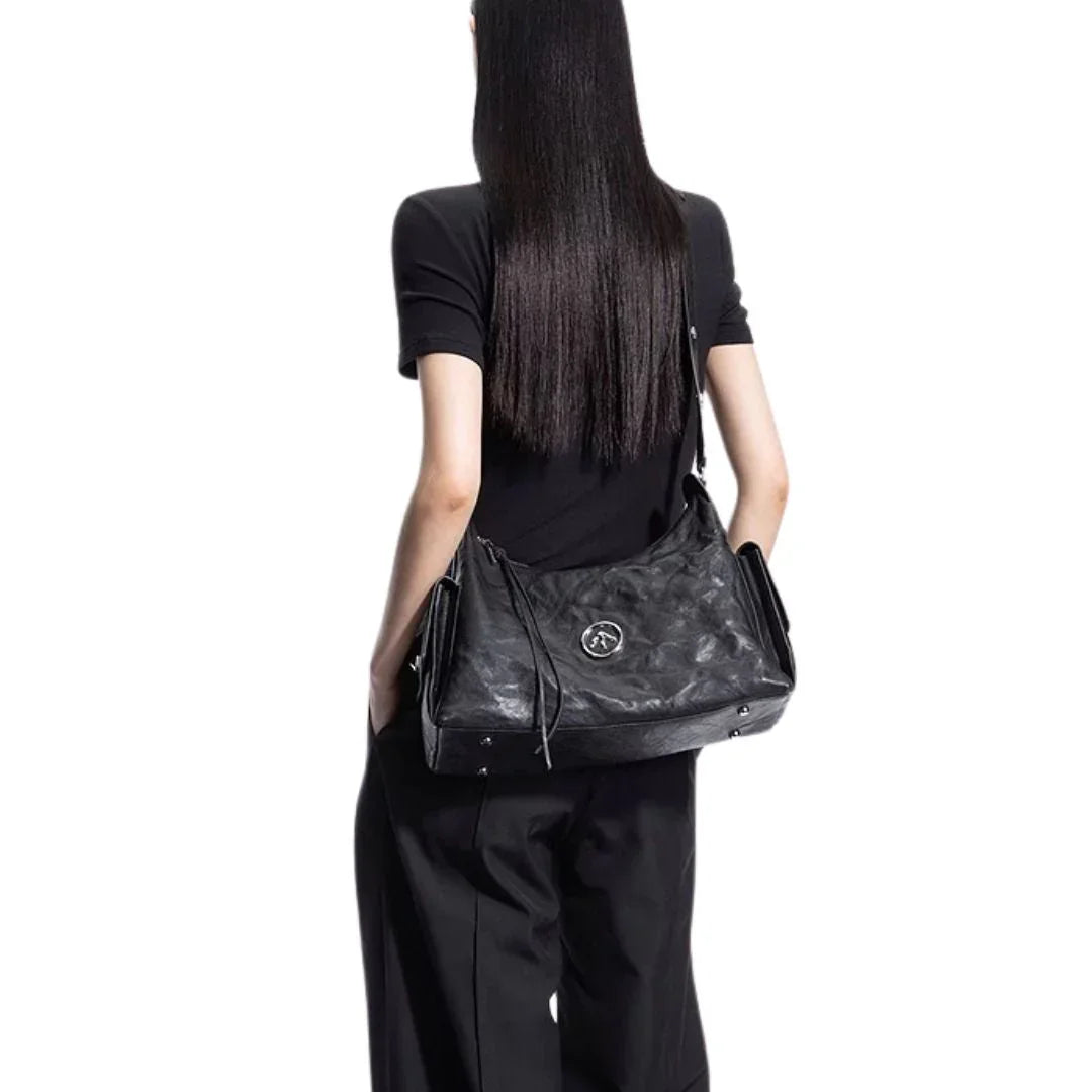 Woman in black outfit carrying large black leather shoulder bag on white background