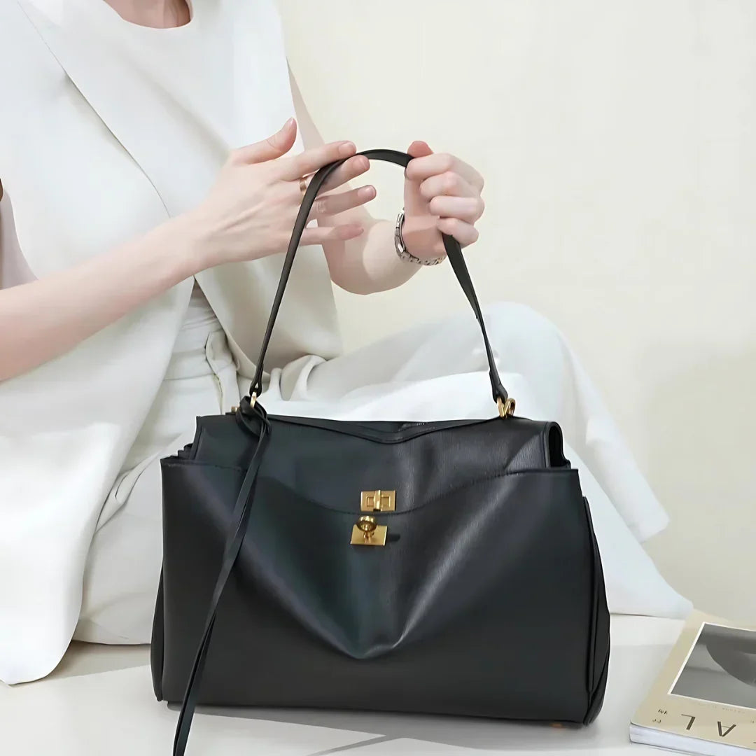 Woman in white suit holding elegant black leather handbag with gold hardware