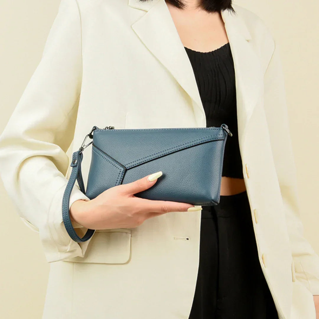 Woman in cream blazer holding blue leather wristlet clutch purse
